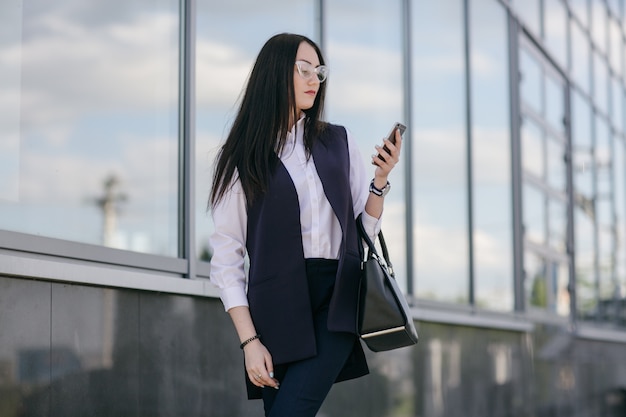 Chica joven de negocios mirando su teléfono inteligente