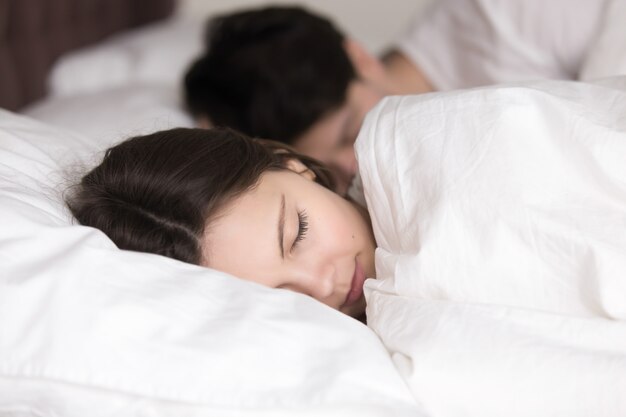 Chica joven con novio durmiendo pacíficamente en acogedora cama blanca