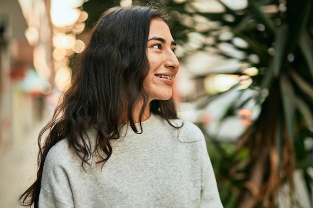 Chica joven de oriente medio sonriendo feliz de pie en la ciudad