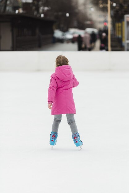 Chica joven patinar sobre hielo tiro posterior