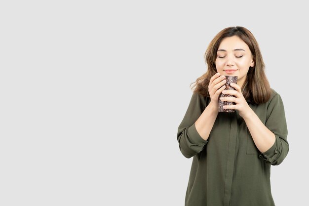 Chica joven de pelo corto con taza de café con leche de pie y posando. Foto de alta calidad