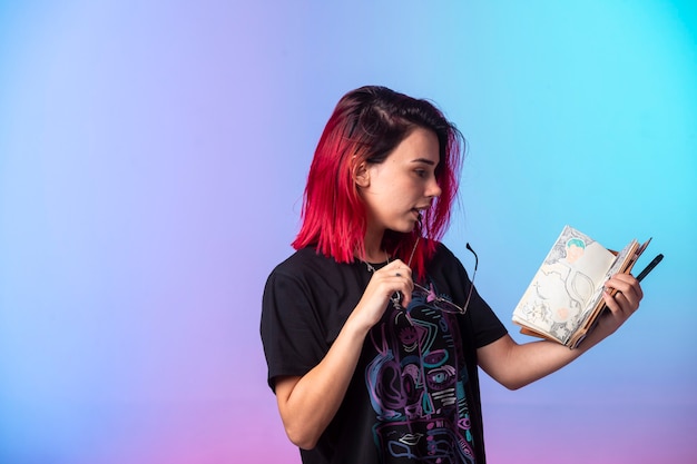 Chica joven con pelos rosados sosteniendo un cuaderno de bocetos.