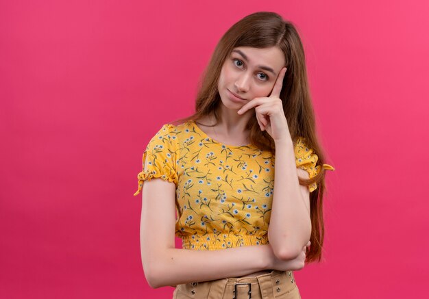 Chica joven pensativa poniendo la mano en la mejilla y mirando en la pared rosa aislada con espacio de copia