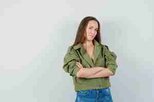 Foto gratuita chica joven de pie con los brazos cruzados en chaqueta, pantalones cortos y mirando confiado. vista frontal.