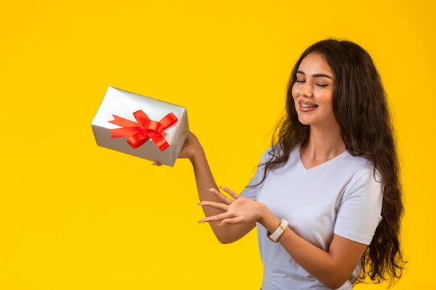 Chica joven posando con una caja de regalo en la mano y mirándolo