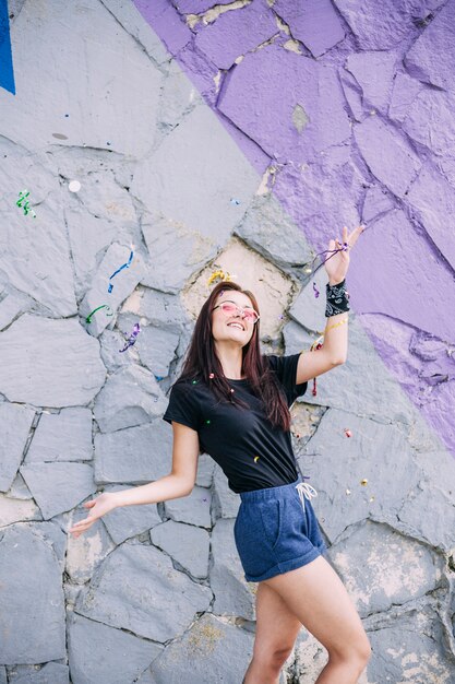 Chica joven posando delante de la pared de piedra pintada