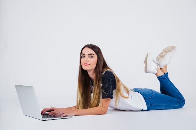Chica joven posando con portátil en el suelo