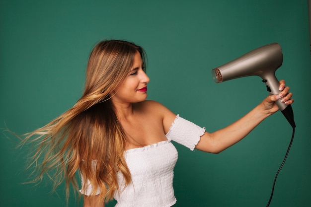 Foto gratuita chica joven posando con secador de pelo