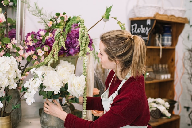 Chica joven que compone flores florecientes