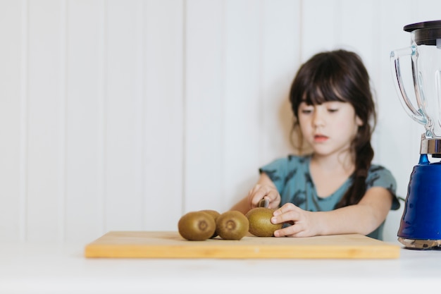 Chica joven que corta el kiwi