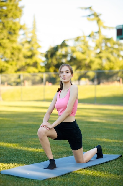 Chica joven que estira su cuerpo en el parque