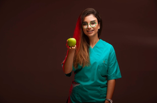 Chica joven que ofrece una manzana verde en la mano.