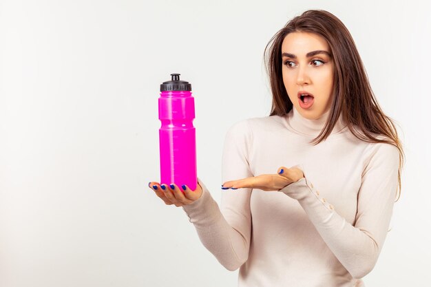 Chica joven que sostiene una botella de agua rosada en el punto de mano en él