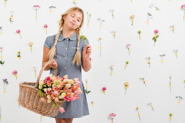 Chica joven que sostiene la cesta con flores