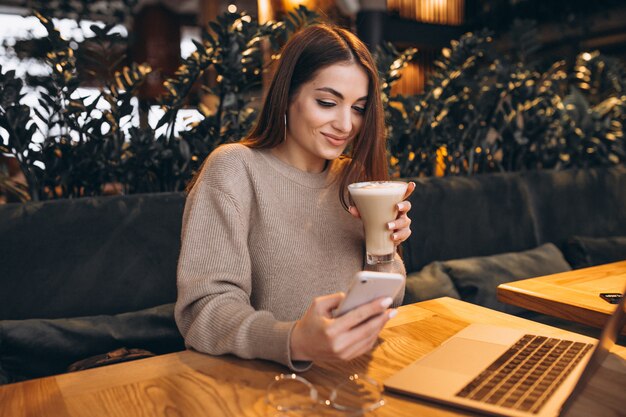 Chica joven que trabaja en una computadora en un café