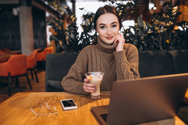 Chica joven que trabaja en una computadora en un café