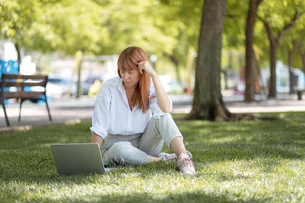 Chica joven que trabaja en una computadora en el parque