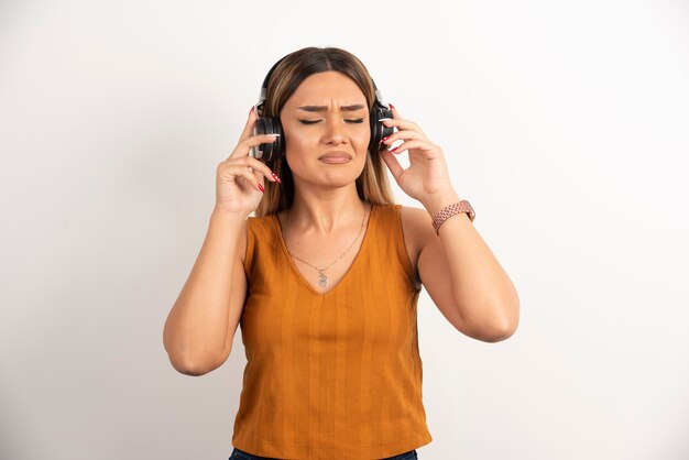 Chica joven en ropa casual posando con auriculares.