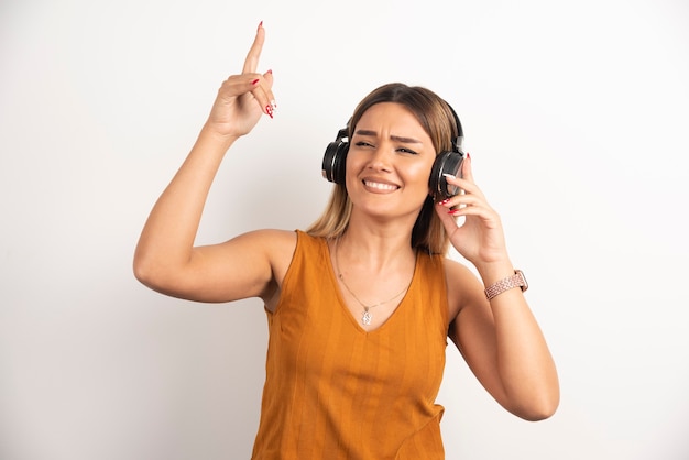 Chica joven en ropa casual posando con auriculares.