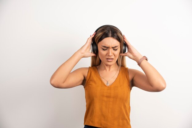 Chica joven en ropa casual posando con auriculares.