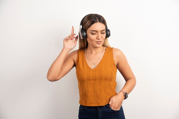 Chica joven en ropa casual posando con auriculares.