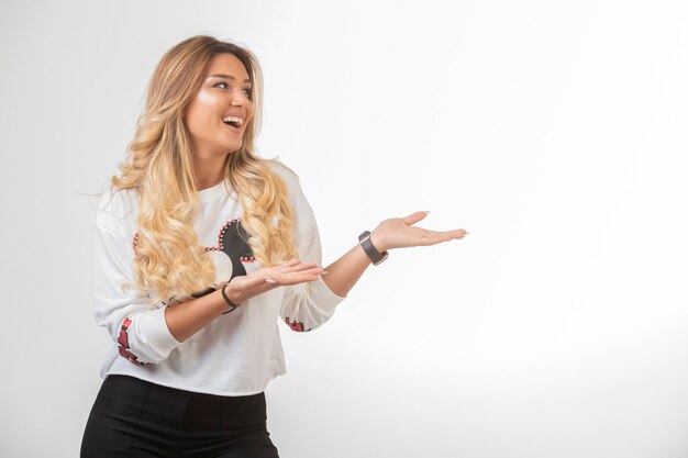 Chica joven en ropa deportiva apuntando algo a la derecha.