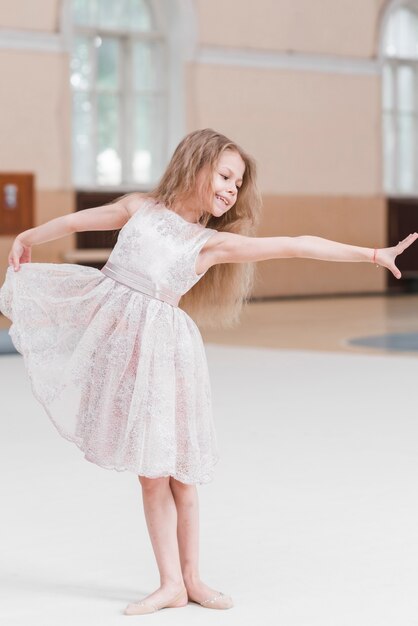 Chica joven rubia bailando ballet en piso en estudio de danza