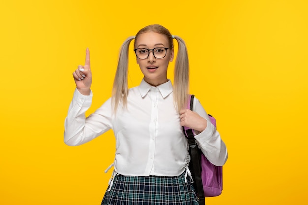 Chica joven rubia del día mundial del libro con colas de caballo sobre fondo amarillo