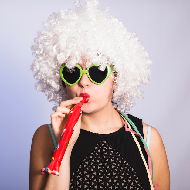 Chica joven con silbato, peluca y gafas de sol