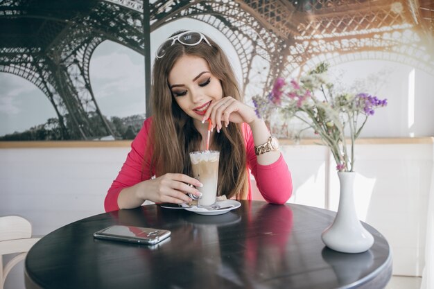 Chica joven sonriendo bebiendo un batido de chocolate