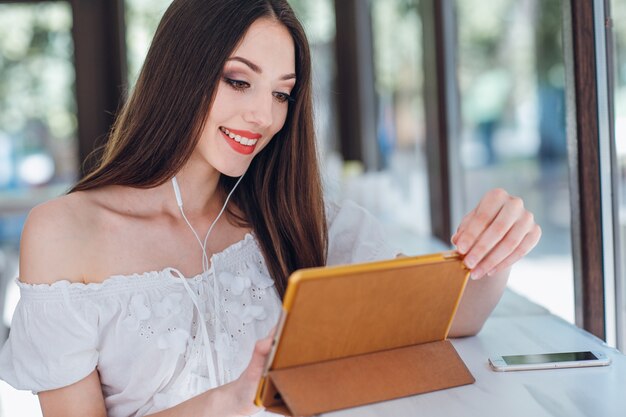 Chica joven sonriendo mientras mira una tablet con auriculares