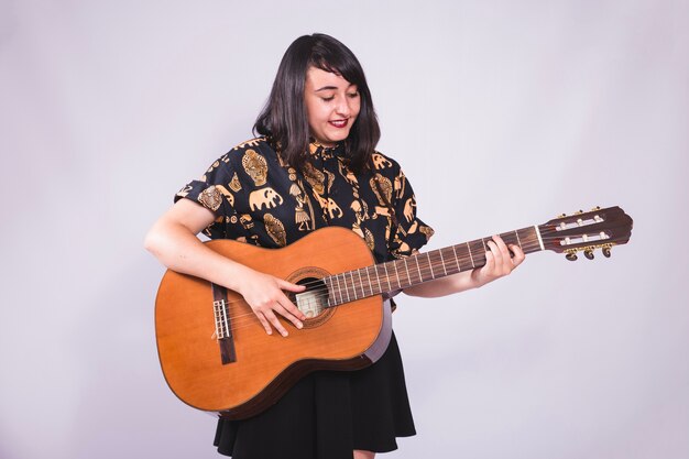 Chica joven sonriendo y posando con la guitarra