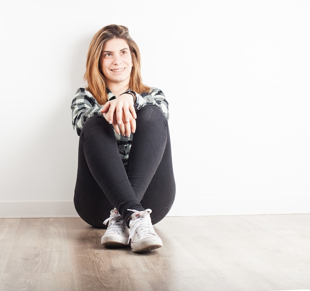 Foto gratuita chica joven sonriendo sentada en el suelo