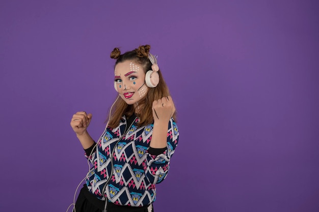 Chica joven con soporte de maquillaje creativo sobre fondo púrpura. foto de alta calidad