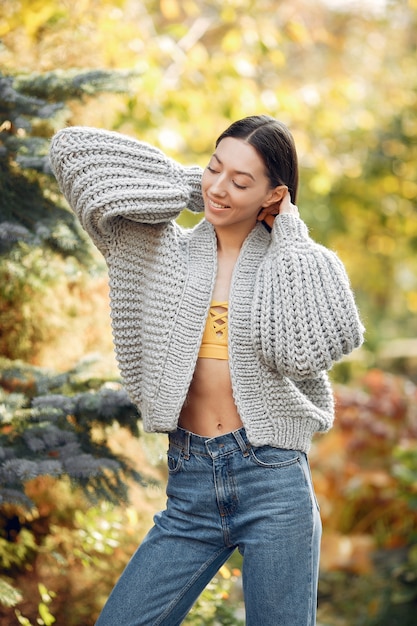 Foto gratuita chica joven en un suéter gris posando al aire libre