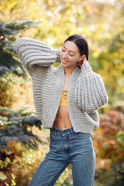 Chica joven en un suéter gris posando al aire libre