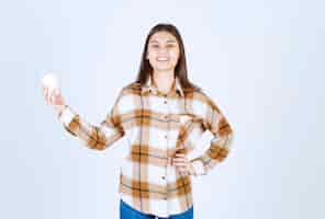Foto gratuita chica joven con taza de té de pie sobre la pared blanca.