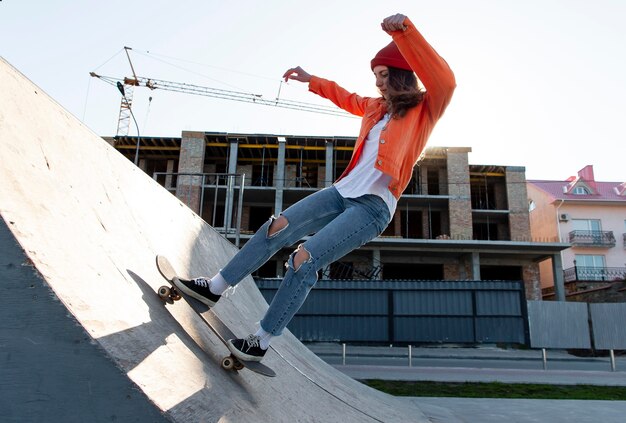 Chica joven de tiro completo en patineta