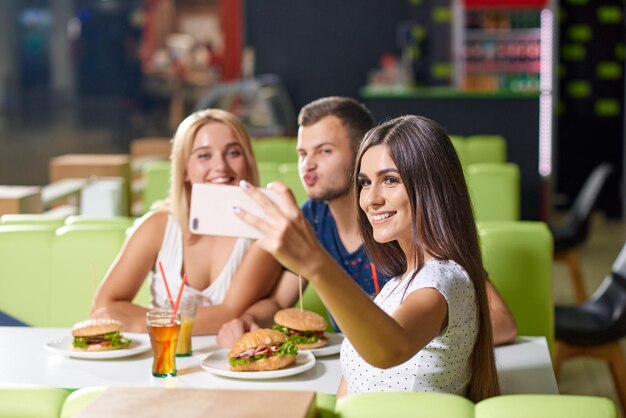 Chica joven tomando selfie junto con amigos felices