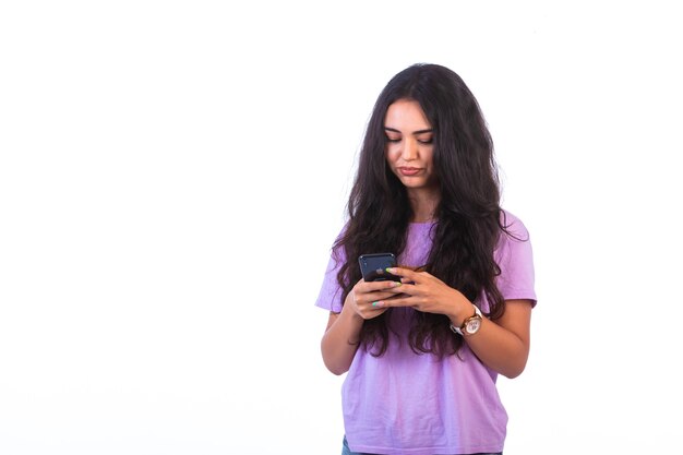 Chica joven tomando selfie o haciendo una videollamada sobre fondo blanco y se ve seria