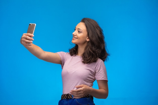 Chica joven tomando selfie con su teléfono inteligente.