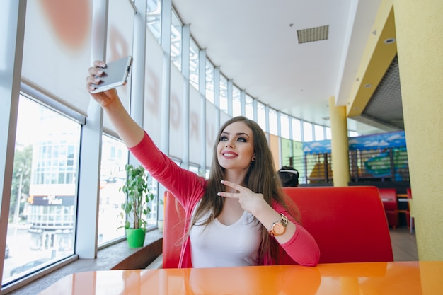 Foto gratuita chica joven tomándose una foto con el brazo en alto