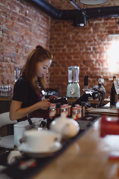 Una chica joven trabaja en un café en el bar.