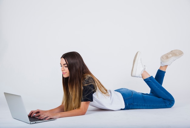 Chica joven trabajando tumbada