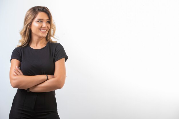 La chica joven con trajes deportivos negros se siente segura y positiva.