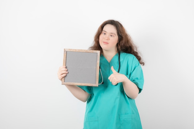 chica joven en uniforme verde con un marco que muestra un pulgar hacia arriba.