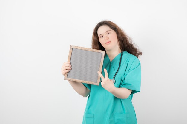 chica joven en uniforme verde con un marco que muestra el signo de la victoria.