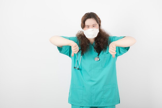 chica joven en uniforme verde mostrando los pulgares hacia abajo.