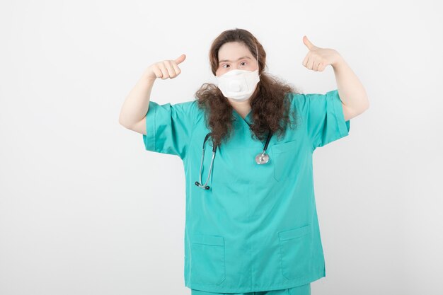 chica joven en uniforme verde mostrando los pulgares para arriba.