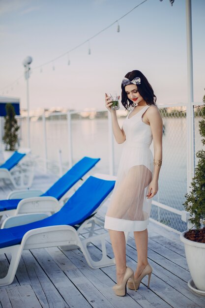 Chica jóven con un vestido blanco y una copa en la mano